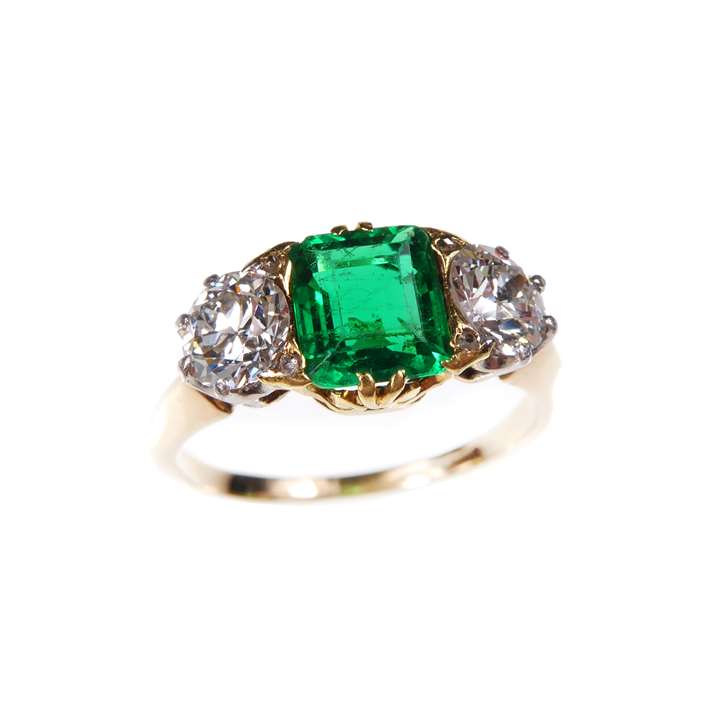 Emerald and diamond three stone ring, the central Colombian emerald of rectangular trap cut